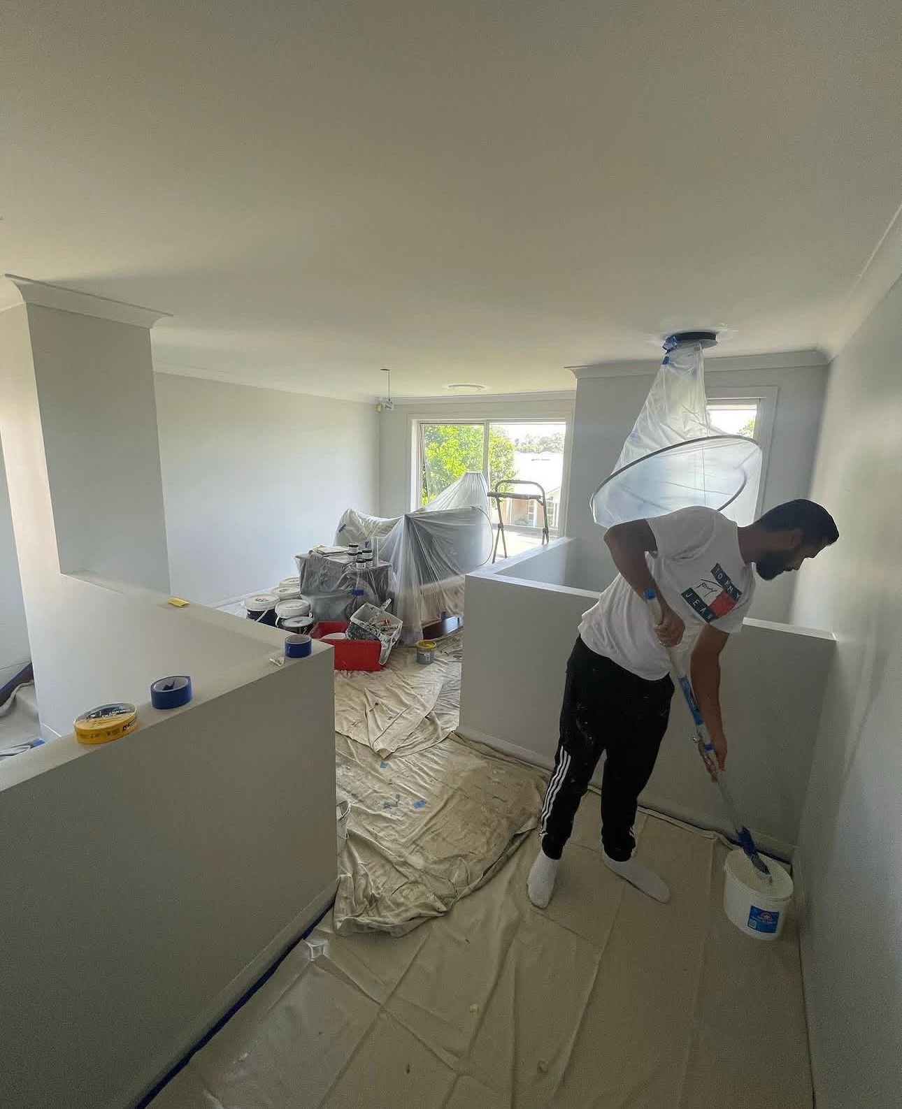 Interior painting in progress with furniture protected and drop sheets down in a Wollongong home